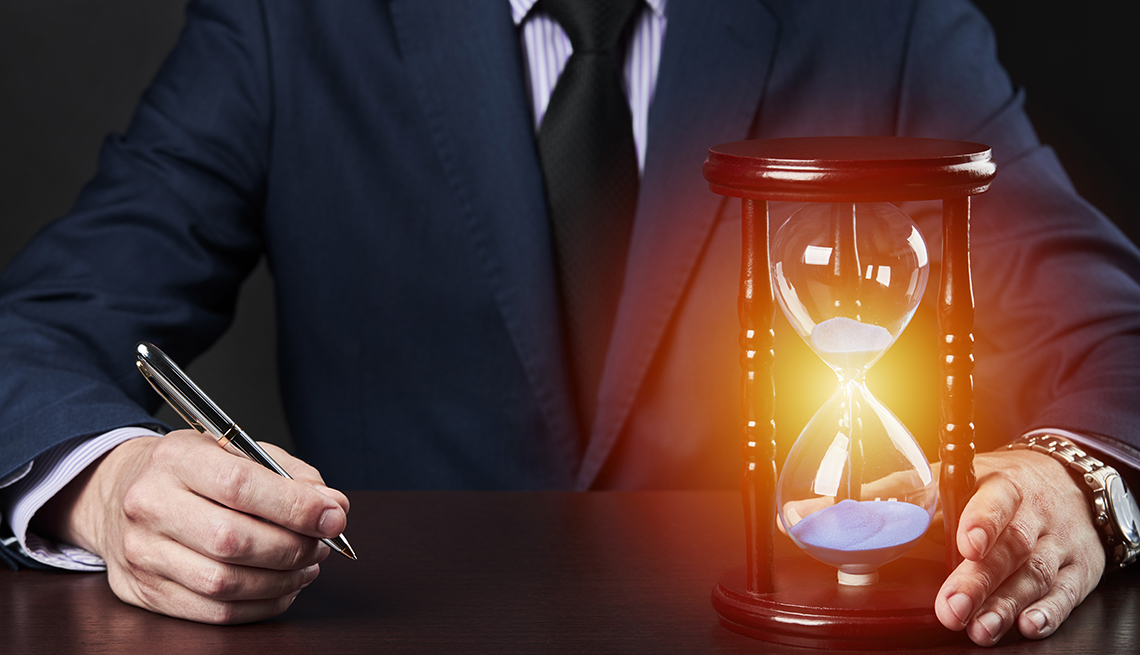 torso of a businessman holding a pen and an hourglass that is glowing red